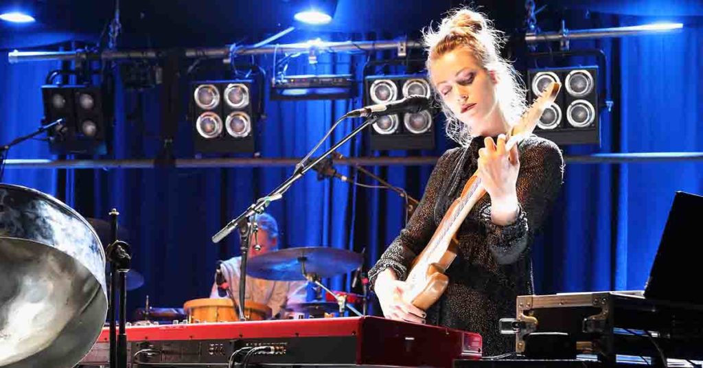 Image of a live performance with a woman playing guitar.