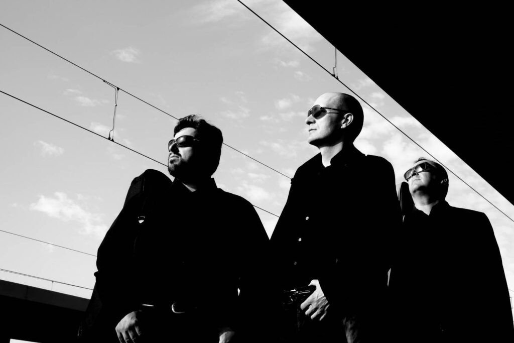Steel and Velvet standing together in a moody black and white setting with train wires above them
